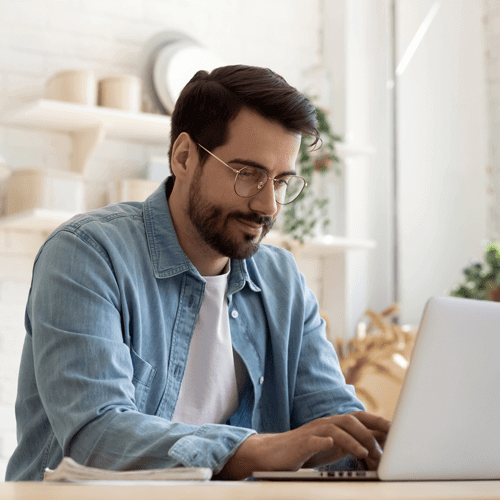 a man sat in front of his laptop as he types